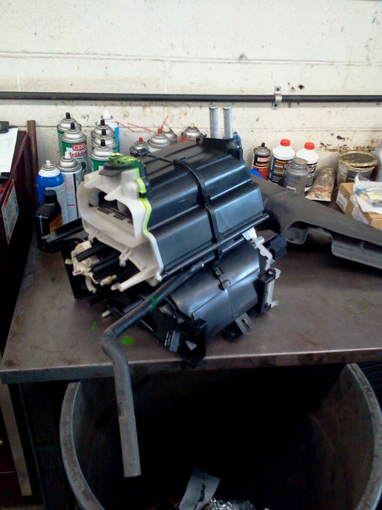 A heater box placed on a table alongside several spray bottles, suggesting maintenance or repair work on heating systems